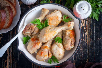 Fried chicken drumsticks in a pan on a wooden table, top view, selective focus