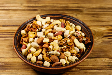 Mixed nuts on wooden table. Walnuts, pistachio, almond, peanut, cashew, hazelnut in ceramic bowl. Healthy eating concept