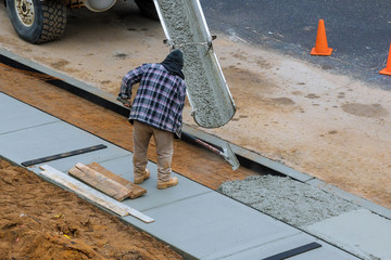 Pouring in process of pouring concrete cement on newly paved sidewalk