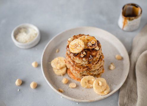 healthy oatmeal pancake with banana, hazelnut, syrup. gray concrete background, top view, horizontal image