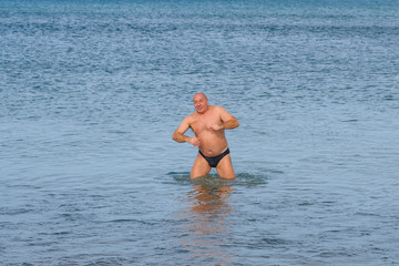 A man is swimming in the sea off the coast.