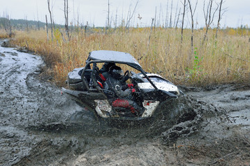 Obraz na płótnie Canvas Amazing UTV driving in mud and water at Autumn day