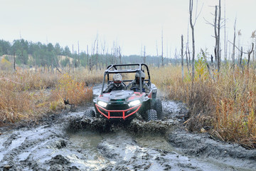 Obraz na płótnie Canvas Amazing UTV driving in mud and water at Autumn day. Mud splash 
