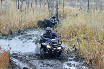 Cool picture of active ATV and UTV driving in mud and water at Autumn