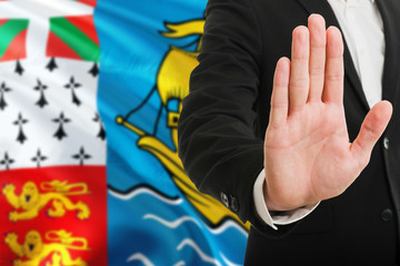 Saint Pierre And Miquelon rejection concept. Elegant businessman is showing stop sign with hand on national flag background.