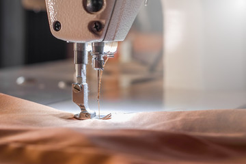 Needle of white industrial sewing machine use sew cloth close-up.