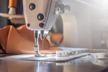 Needle of white industrial sewing machine use sew cloth with tape measure close-up.