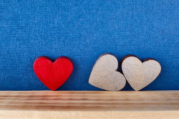 Red wooden heart and 2 silver colors on a blue background for design for Valentine's Day. Symbol of an unconventional modern family, threesome love