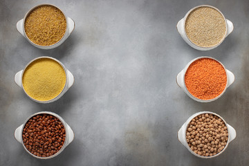 set of raw cereals (bulgur, couscous, beans, quinoa, lentils, chickpeas). food frame, place for text. gray background, top view