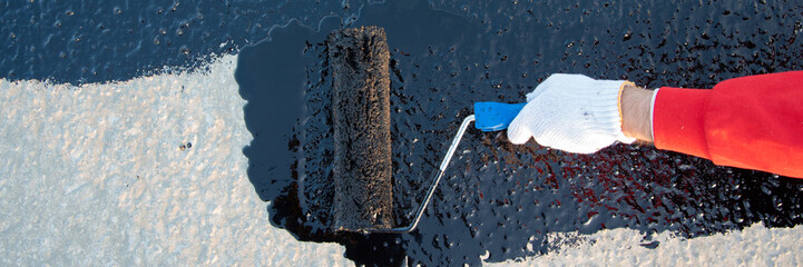 Worker applies bitumen mastic on the foundation