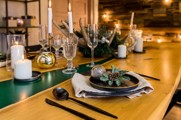Stylish table setting with burning candles and Christmas decorations.Stylish Christmas interior . Festive decor and Modern style interior.warm and cozy evening in Christmas interior design. Many white