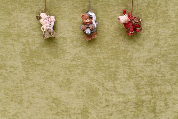 Christmas toys, snowman, teddy bear and deer, suspended at the top, on a green plush background.
