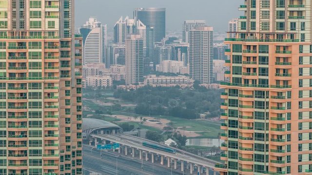 Metro station near Dubai Internet City and Dubai Media City districts as well as Golf Club evening timelapse. Aerial view from Dubai marina with traffic on a highway. Greens and tecom district on