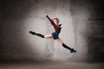Fototapeta na wymiar Ballerina in a jump on a gray background. Feet, dance, modern dance, classical dance, stretching, active, fitness body