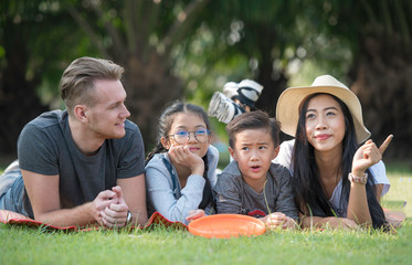 Happy family day vacation spend time together, lying on green grass in the park.