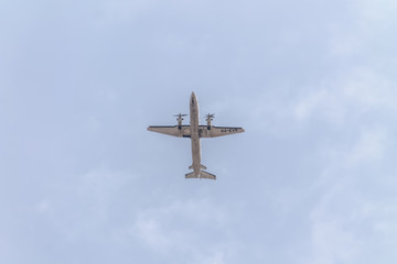 Underside view of a commercial airliner flying, blue sky as background