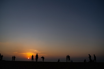 Fototapeta na wymiar People standing while watching sunset on the beach of Nai Yang in Phuket (Thailand)