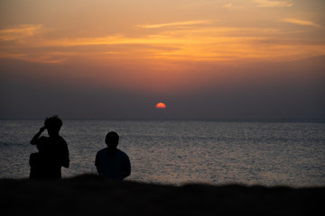 Naklejka na ściany i meble People standing while watching sunset on the beach of Nai Yang in Phuket (Thailand)