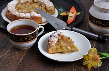 Sweet Homemade fruit tart, tea and sweets on a dark wooden table.