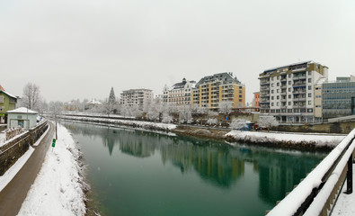 Fototapeta premium Panorama of the River Drau crossing the town of Villach in Austria in a winter day during a snow storm