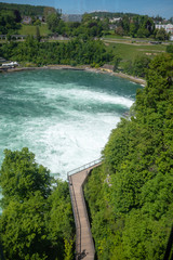 Beautiful view of wooden walkway beside big flowing river  with fresh green trees for background , copy space