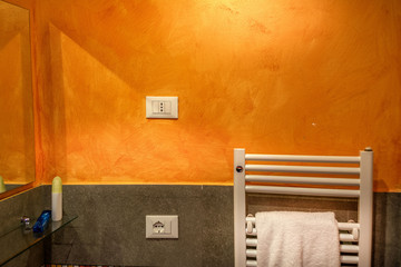 Towel warmer and electric socket on an orange wall