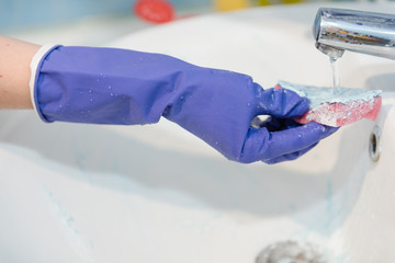 The girl cleans the bathroom, clean the ceramic sink in the bathroom, wash with rubber gloves,...