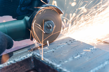Cut metal with a Angular grinding machine. Sparks are flying. Construction tool grinder. A man is...