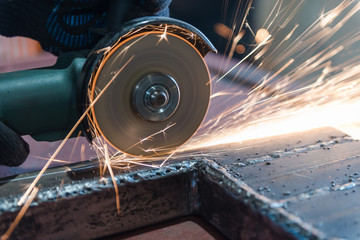 Cut metal with a Angular grinding machine. Sparks are flying. Construction tool grinder. A man is cutting metal. Wear gloves for safety.