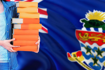Cayman Islands national education concept. Close up of female student holding colorful books with country flag background.