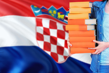 Croatia national education concept. Close up of female student holding colorful books with country flag background.