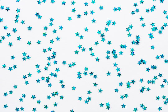 Iridescent Blue color stars. Glitter confetti on white festive background. Holiday Sparkles. Flat lay.