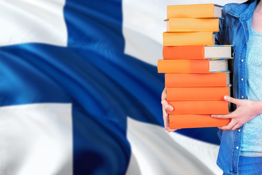 Finland national education concept. Close up of female student holding colorful books with country flag background.