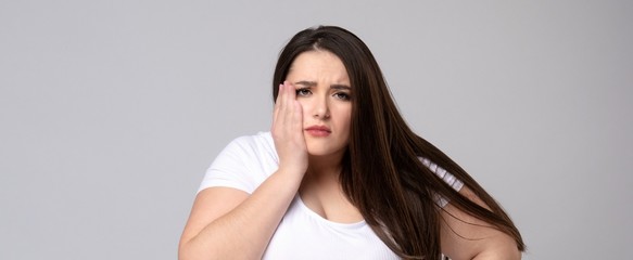 Plus Size Model with a hand holding a sore tooth