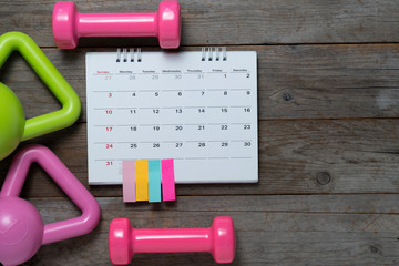 Time for exercising with calendar and sport equipment on the wooden table background