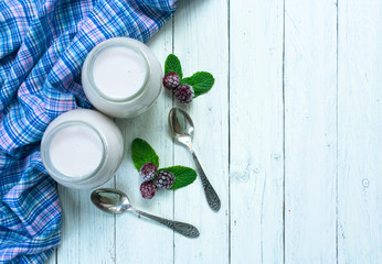 Blackberry yogurt in jars on a white wooden background. Top view. Copy space.