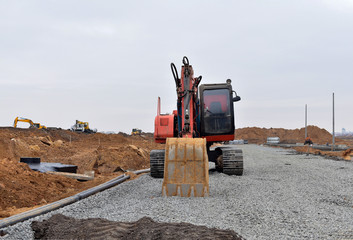 Excavator with a large iron bucket on a construction site during road works. Backhoe dig the ground...