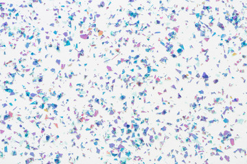 Glowing mica glitter confetti on white background. Festive abstract backdrop. Holiday Flat lay.