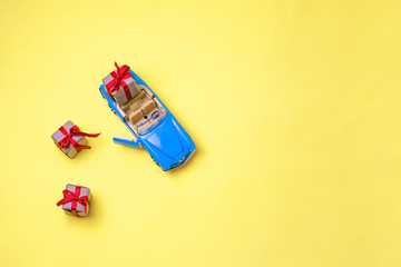 Miniature mini toy.Blue toy car with open top convertible carrying a gift with a red bow on a...