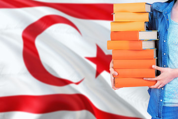 Northern Cyprus national education concept. Close up of female student holding colorful books with country flag background.