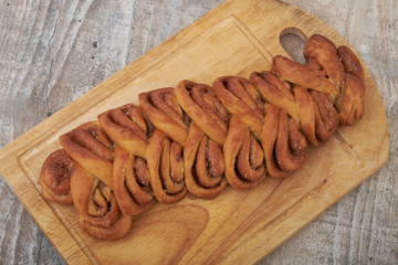 Twisted traditional Swedish cinnamon rolls at a café. The sweet buns are on a wooden chopping board.