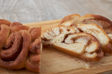 Twisted traditional Swedish cinnamon rolls at a café. The sweet buns are on a wooden chopping board.
