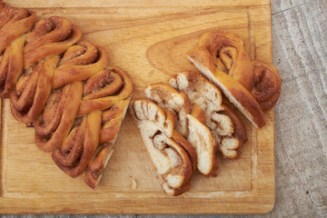 Twisted traditional Swedish cinnamon rolls at a café. The sweet buns are on a wooden chopping board.