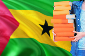 Sao Tome And Principe national education concept. Close up of female student holding colorful books with country flag background.