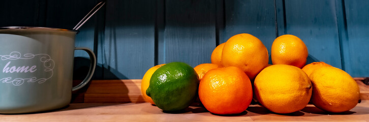 Citrus fruits on wooden background. Lime, lemon, tangerine on wooden table and blue background.