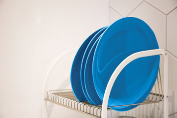 Fototapeta na wymiar many plates on a stand on a kitchen drain, color 2020 classic blue