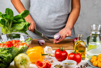Woman cuts onions and makes salad in the kitchen. Healthy diet concept.