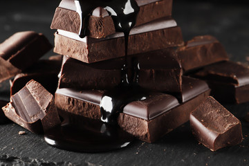 melted chocolate pouring into a piece of chocolate bars   on a dark  table