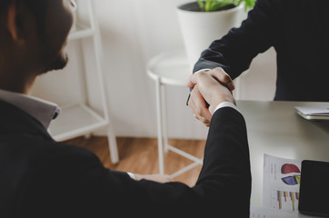 Deal. business people smiling and shaking hands with partner after finishing up a meeting with document on desk in office room, partnership, negotiation, business meeting and teamwork concept