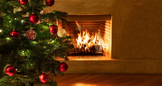 Christmas tree close up on burning fireplace background